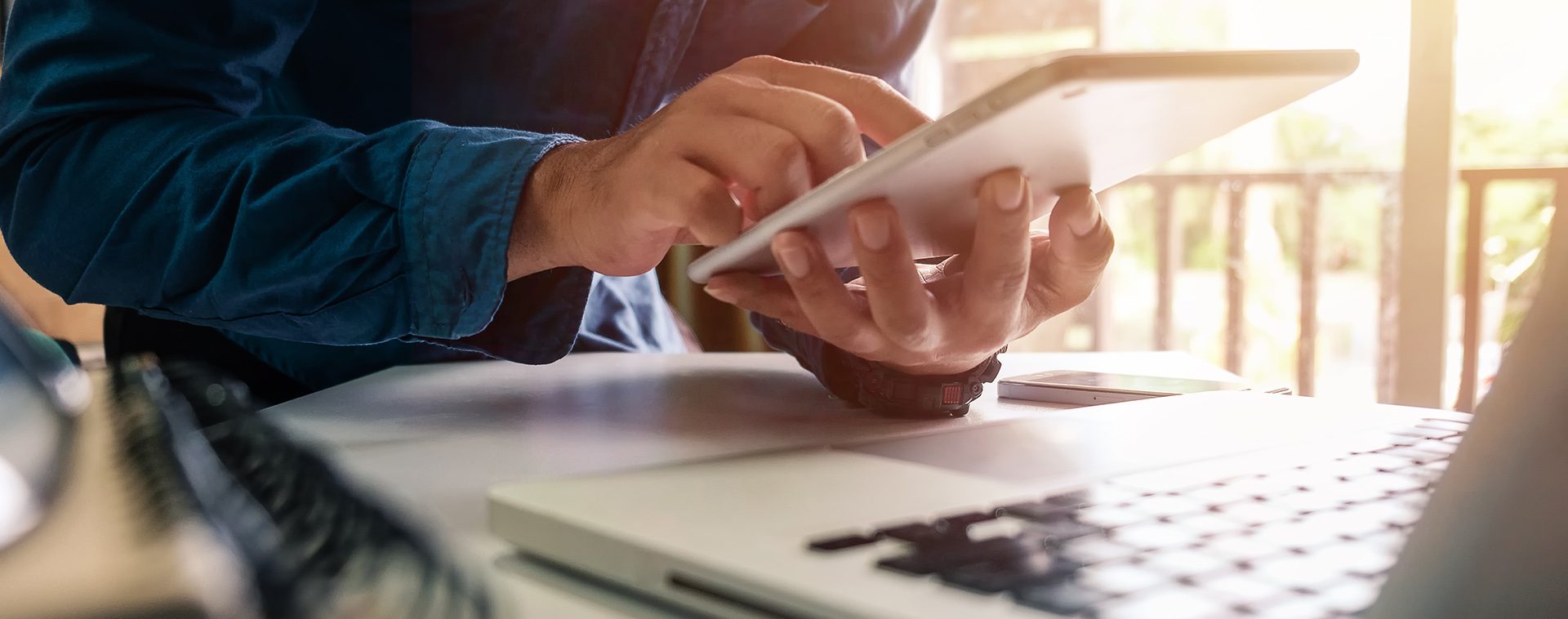 A picture of a man using a tablet computer and a laptop