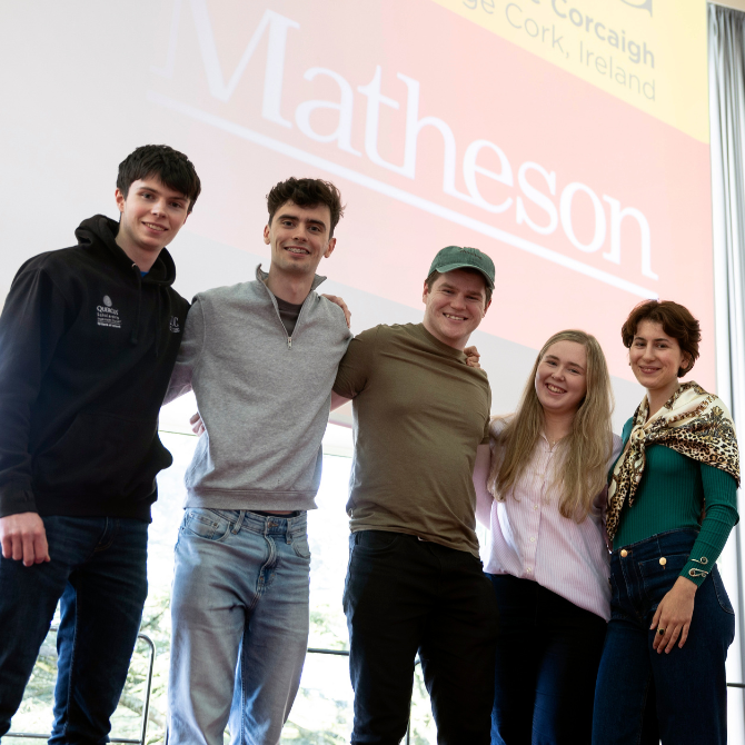 Five people stand together on a stage in front of a large projected screen displaying the Matheson logo. The group is posed shoulder-to-shoulder with arms around one another, facing the camera. The backdrop includes event branding and references to Cork, Ireland. The individuals are dressed in a mix of casual and business-casual clothing, and the photo appears to have been taken at a student or innovation-focused event.